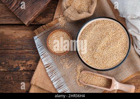 Semi bianchi di quinoa in una ciotola su un fondo di legno marrone. Foto Stock