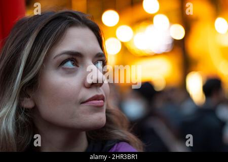Una ragazza che guarda in su mentre una cantante cantava dietro di lei. Ragazza bionda davanti allo sfondo giallo flur. Primo piano. Foto Stock