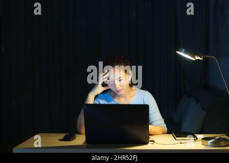 Donna asiatica lavoro a tarda notte stressante con i problemi di ricerca di progetto su un computer portatile o notebook a casa ufficio burnout sindrome concetto. Foto Stock