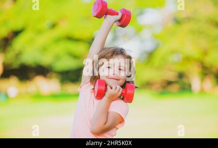 Bambino sportivo con manubri. Sport per bambini. Ragazzo che si esercita nel parco. Uno stile di vita attivo e sano. Foto Stock