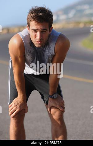 Catturando il respiro. Giovane runner stanco che si appoggiava per prendere il respiro. Foto Stock