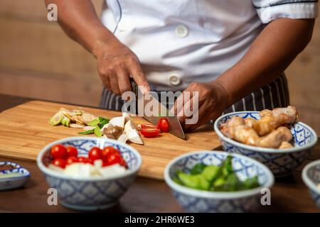 Processo di cottura, donna che taglia i pomodori per la pasta di melanzane dalle melanzane immagazzinate Foto Stock