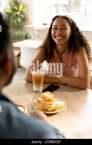 Allegra giovane donna afroamericana seduta con l'uomo al tavolo in caffetteria Foto Stock