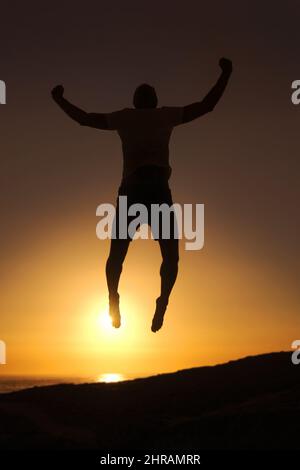 Libero e in sintonia con il mondo. Silhouette di un uomo che salta in aria con il tramonto sullo sfondo. Foto Stock