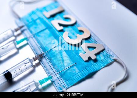 Quarto vaccino covid sparato e concetto jab con maschera facciale. Quattro siringhe sono considerate nella tabella come un concetto per la dose di vaccino 4th covid-19, chiamata anche Foto Stock