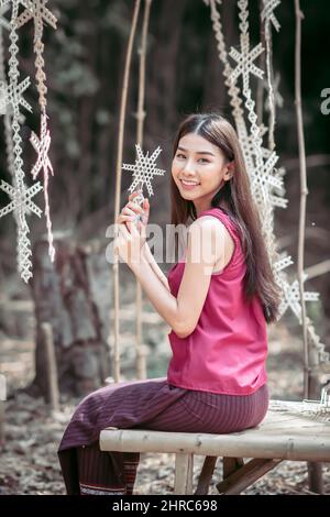 Ritratto di una donna sorridente seduta su una panchina in un villaggio rurale, Thailandia Foto Stock