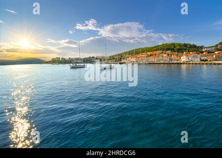 Nel tardo pomeriggio la luce del sole sulla costa dalmata del mare Adriatico con le barche nel porto e una piccola città vicino all'isola di Hvar Croazia Foto Stock