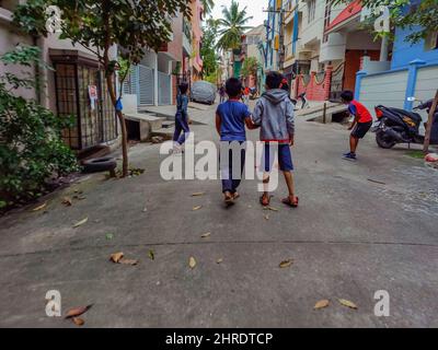 Gruppo di bambini che giocano a cricket sulla strada nella zona residenziale Foto Stock