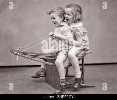 1930S RIDENDO SORRIDENDO RAGAZZO E RAGAZZA SEDUTI SUL RETRO DELLA SEDIA WINDSOR FINGENDO CHE SIA UN CAVALLO O UNA CARROZZA O. ANCHE UN INVERNO SLED - J3228 HAR001 HARS FEMMINE FRATELLI STUDIO SHOT SLED SALUTE HOME VITA COPIA SPAZIO AMICIZIA FULL-LENGTH PERSONE MASCHI FRATELLI SORELLE SORELLE B&W CARROZZA RISINE FELICITÀ ALLEGRO E FRATELLO CHE FINGE AMICHEVOLE IMMAGINARIA IMMAGINAZIONE GIOIOSA IMMAGINATA O WINDSOR CREATIVITÀ NERO E BIANCO ETNIA CAUCASICA ANCHE HAR001 FANNO CREDERE VECCHIO STILE Foto Stock