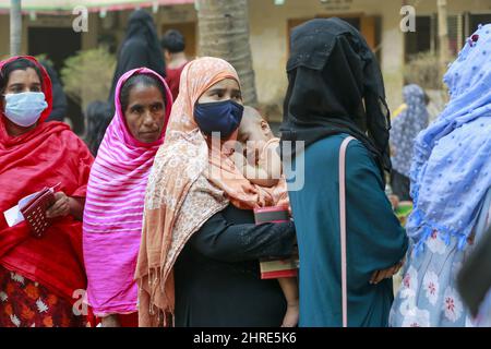 La gente attende in coda per ricevere il vaccino Covid-19 in un centro di inoculazione, a Narayanganj, Bangladesh, 25 febbraio 2022. Alcuni centri di vaccinazione sono stati sopraffatti quando migliaia di persone si sono rivolte per cercare di ottenere la prima dose di vaccino contro il coronavirus il venerdì, un giorno prima dell’inoculazione di 10 milioni di persone in un unico giorno di guida nazionale. Le persone che sono arrivate alle 6am presso il centro della Delpara High School di Narayanganj Sadar Upazila's Kutubpur hanno accodato per nealy sei ore per ottenere le loro dosi di vaccino COVID. Il governo smetterà di somministrare ai cittadini le prime dosi di vaccino contro il coronavirus dopo il 1 Foto Stock