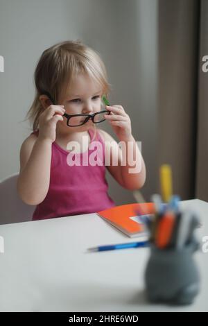 piccola ragazza divertente in eyeglasses che scrive e che disegna alla  tabella Foto stock - Alamy