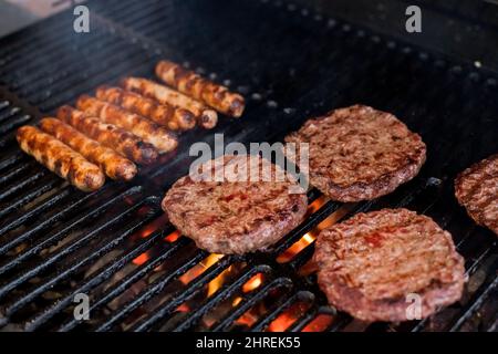 Hamburger affumicati grigliate di carne per hamburger. Friggete sul fuoco aperto sulla griglia - bbq.Burgers e salsicce che cuocono su Flames sul Grill. Foto Stock