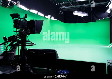 La fotocamera sul treppiede, il proiettore a LED, il faretto, il prompt e un monitor su sfondo verde. Il tasto chroma. Schermo verde. Settore broadcast Foto Stock