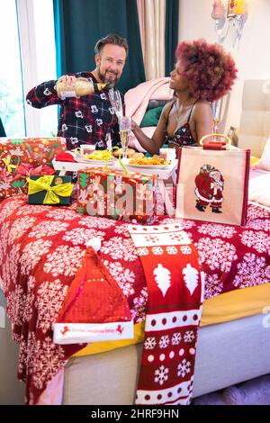Bellissimo scatto verticale della coppia multirazziale che ha la colazione di Natale Foto Stock