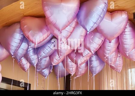 stile di vita. Palloncini sotto il soffitto. San Valentino sfondo giorno. Molto cuore a forma di palloncini con elio all'interno sono volare sotto il soffitto in Foto Stock