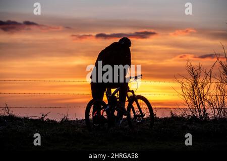 Brighton, Regno Unito. 25th Feb 2022. Brighton, febbraio 25th 2022: Un ciclista guarda il tramonto dal Dike del Diavolo, nel South Downs National Park, appena a nord di Brighton Credit: Andrew Hasson/Alamy Live News Foto Stock