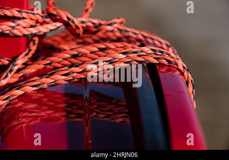 Primo piano e dettaglio di una staffa rossa e blu per esterni con una corda di plastica blu e rossa avvolta intorno ad essa per bloccarla Foto Stock