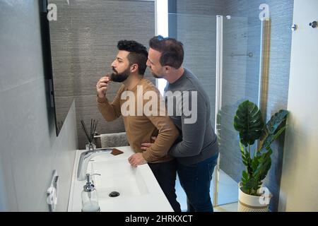 Primo piano di un gay sposato abbracciando nel bagno della loro casa Foto Stock