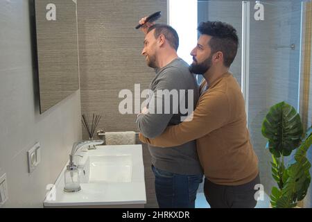 Primo piano di un gay sposato abbracciando nel bagno della loro casa Foto Stock