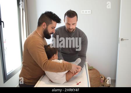 Primo piano di una coppia gay sposata che gioca con la loro figlia Foto Stock