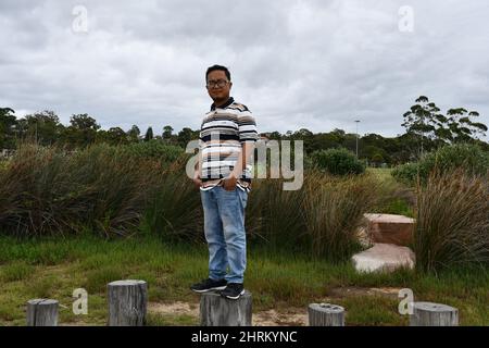 Giovane uomo in piedi sui ceppi nel parco. Foto Stock