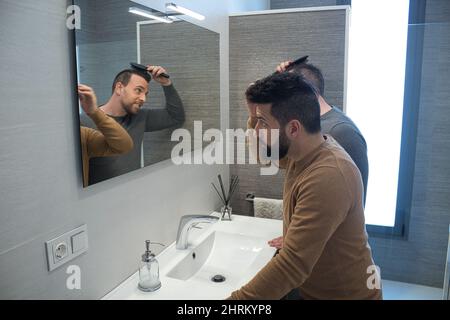 Primo piano di un gay sposato abbracciando nel bagno della loro casa Foto Stock