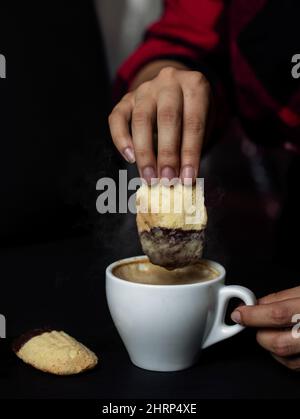 Primo piano di una donna che cava un biscotto in un caffè Foto Stock