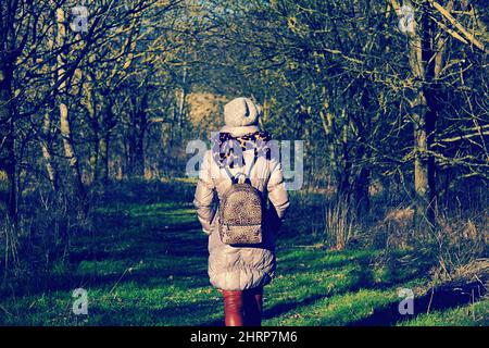 Vista posteriore di una donna elegante che cammina nel verde . Foto Stock