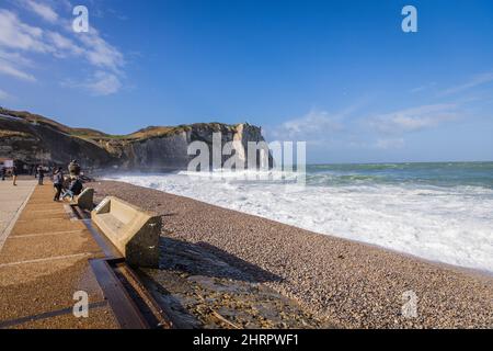 Scogliere di Etretat in Francia e un mare ondulato sotto un cielo blu nuvoloso in una giornata di sole Foto Stock