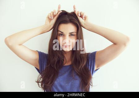 Shes diabolico. Ritratto di una giovane donna attraente che fa corna diavolo. Foto Stock