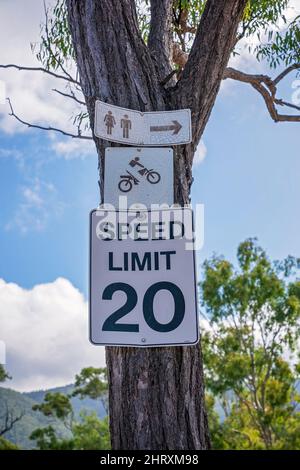 Cartelli inchiodati a un tronco di albero in un campeggio libero all'aperto che mostrano la strada per i servizi igienici pubblici e che indicano il limite di velocità. Foto Stock