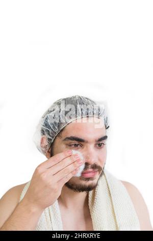 Ritratto di un giovane uomo adulto con una maschera per capelli che puliva il facemask in un salone Foto Stock