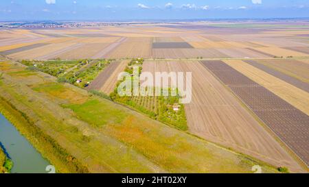 Vista dall'alto su parte del piccolo fiume, canale che va tra campi agricoli, sistema di irrigazione, dopo la raccolta. Foto Stock