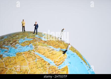 i professionisti in miniatura si levano in piedi su un globo Foto Stock