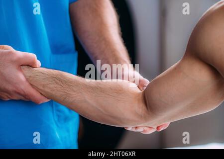 Fisioterapista che tratta il braccio dell'uomo Foto Stock