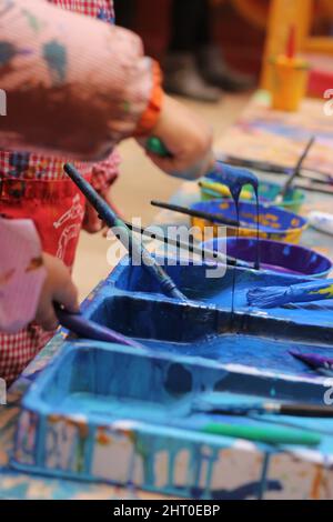 contenitori con vernice e pennelli preparati per fare un murale per bambini Foto Stock