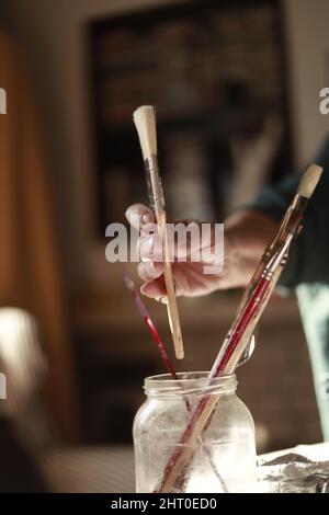 mano donna che tiene le spazzole d'arte in luce naturale Foto Stock
