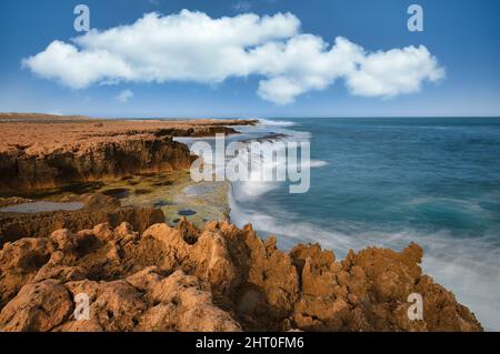 Lunga esposizione cattura delle acque ruvide sulla costa frastagliata dell'Oceano Indiano alla Stazione di Quobba nell'Australia Occidentale. Foto Stock