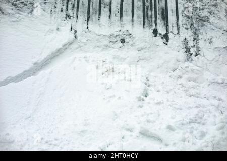 Neve sul muro. Deriva neve su recinzione. La nevicata è caduta dal tetto. Dopo la tempesta di neve. Foto Stock