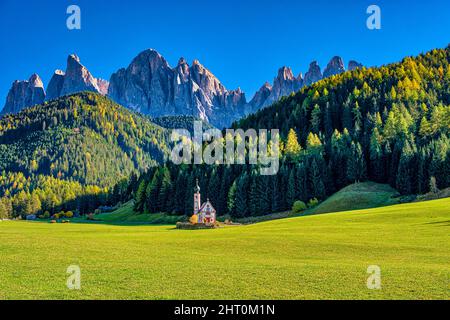 Vista della cappella di San Giovanni in Ranui a San Magdalena nella valle di Villnöss, a nord facce e cime del gruppo Odle in lontananza, in autunno. Foto Stock