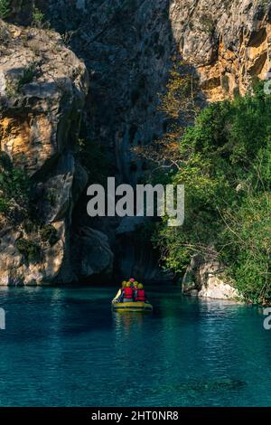 I turisti su una barca gonfiabile galleggiano lungo un canyon roccioso con acqua blu a Goynuk, Turchia Foto Stock