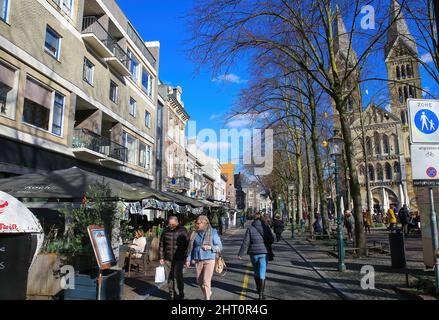 Roermond, Paesi Bassi - Febbraio 9. 2022: Vista sulla strada pedonale con caffè e chiesa medievale nella soleggiata giornata invernale Foto Stock