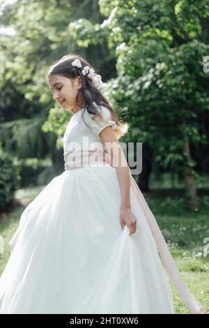 ragazza in prima comunione vestito a piedi nel parco Foto Stock