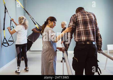 Infermiera femminile che aiuta l'uomo anziano a camminare in casa di cura Foto Stock