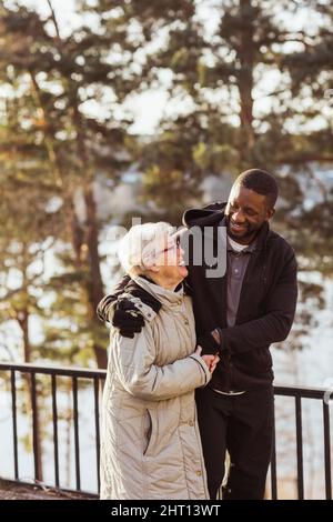 Infermiera sorridente che cammina con una donna anziana nel parco Foto Stock