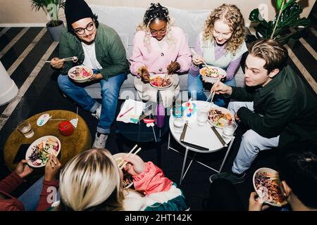 Vista ad angolo alto di studenti multirazziali maschi e femmine che godono di cibo nel dormitorio universitario Foto Stock