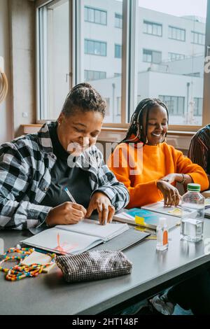 Sorridente studentesse che studiano insieme in classe all'università della comunità Foto Stock