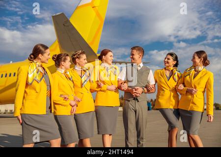 I lavoratori allegri delle compagnie aeree si trovano all'aperto in campo aereo Foto Stock
