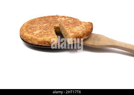 Frittata di patate, conosciuta come 'frittata panish'. Con un cucchiaio di legno. Molto consumato in Spagna. Isolato su sfondo bianco. Cucina spagnola. Foto Stock