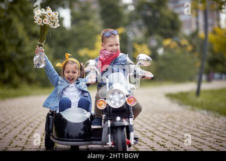felice caucasico bambini in autunno parco guida moto giocattolo Foto Stock